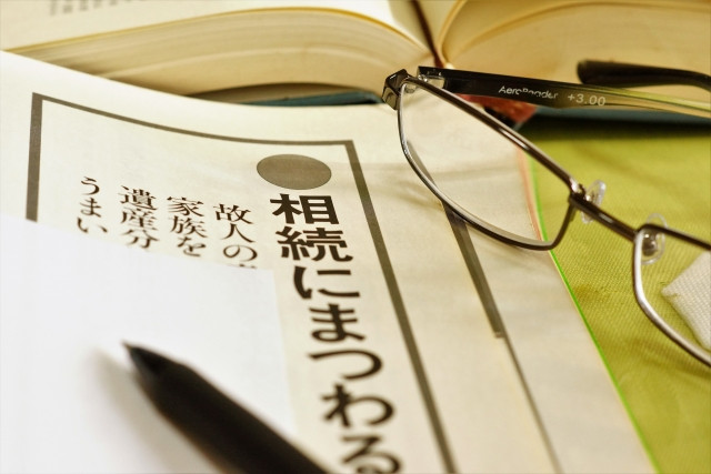 相続に関する本と眼鏡とメモとペン